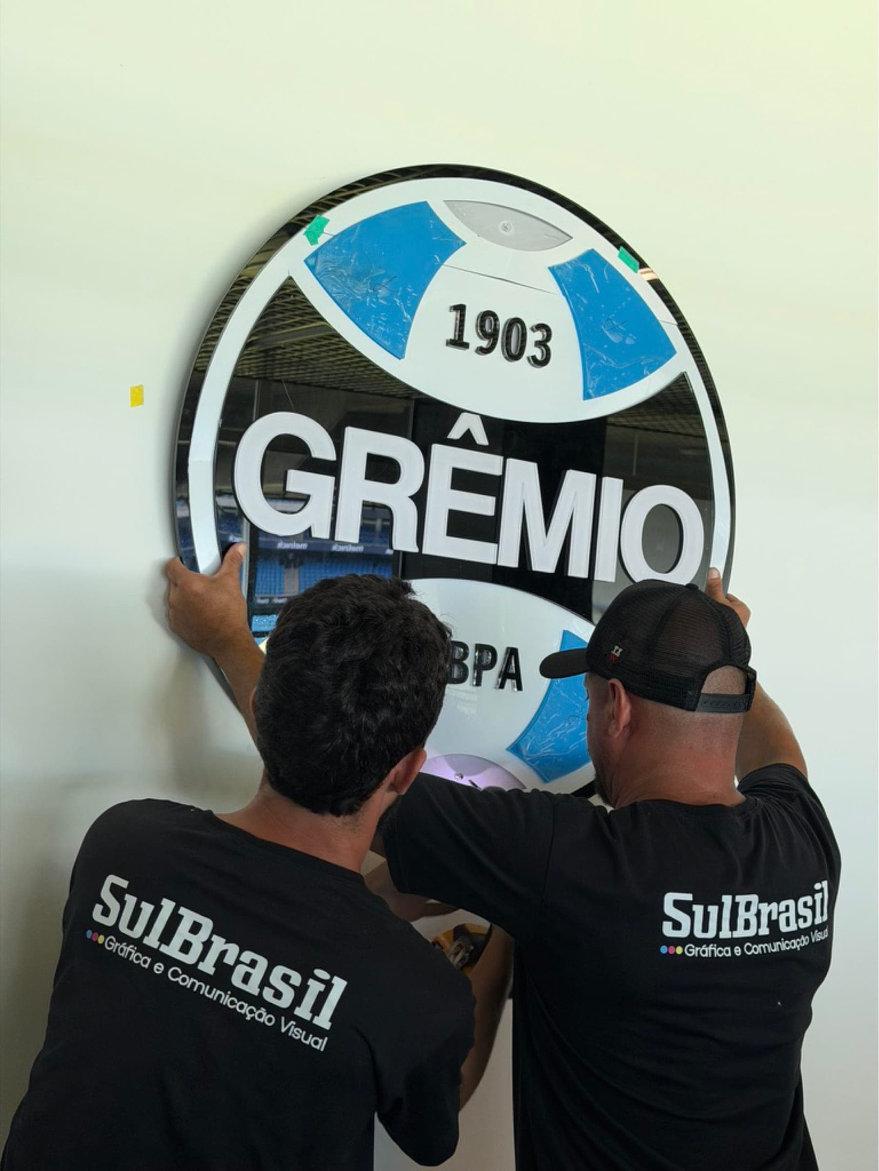 Equipe da SulBrasil instalando escudo do Grêmio em acrílico